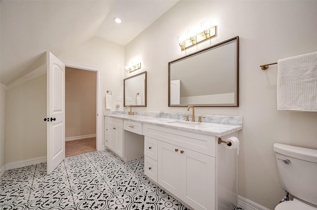 bathroom featuring toilet, vanity, and vaulted ceiling