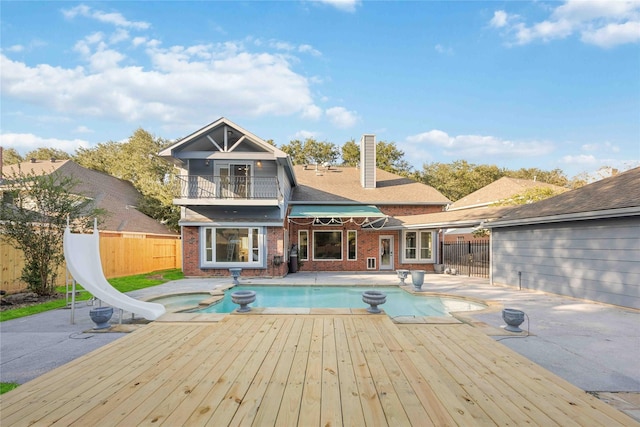 view of pool featuring a jacuzzi, a patio, a wooden deck, and a water slide