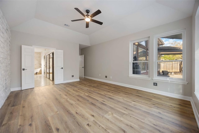 unfurnished bedroom featuring a tray ceiling, ceiling fan, and light hardwood / wood-style floors