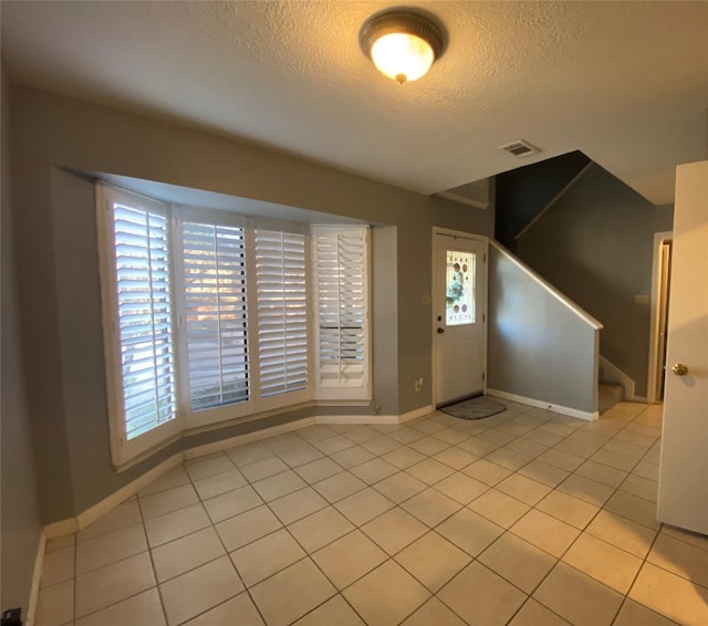 tiled entrance foyer with a textured ceiling and a wealth of natural light