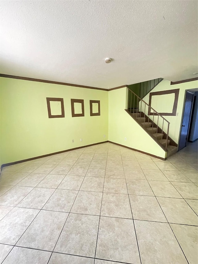 tiled spare room with a textured ceiling and crown molding