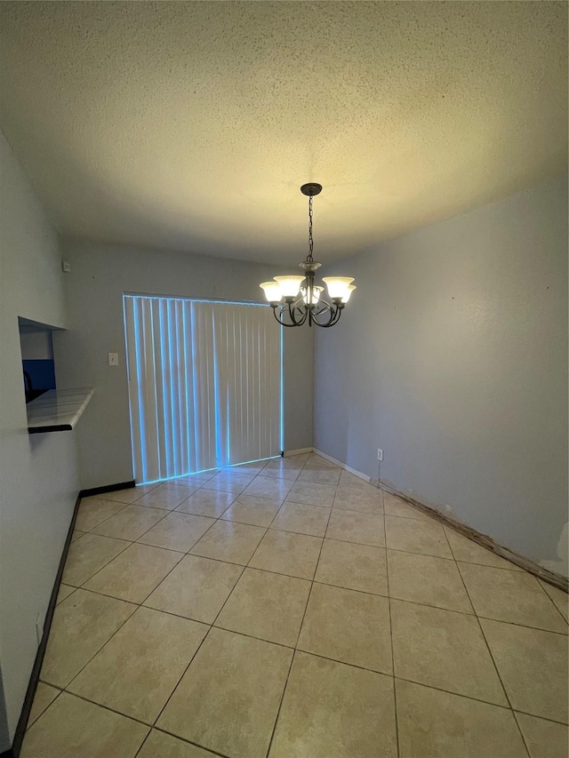 unfurnished dining area with a chandelier, a textured ceiling, and light tile patterned flooring