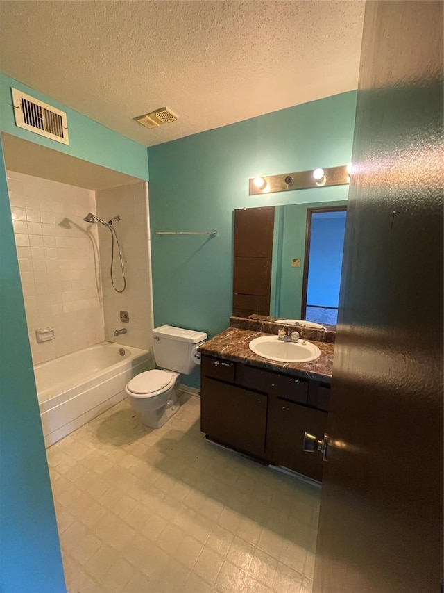 full bathroom with tiled shower / bath combo, toilet, a textured ceiling, and vanity