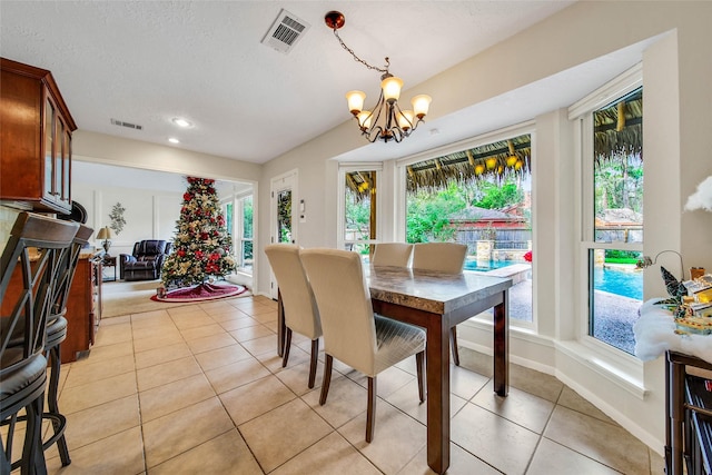 dining area with a textured ceiling, a notable chandelier, and light tile patterned flooring