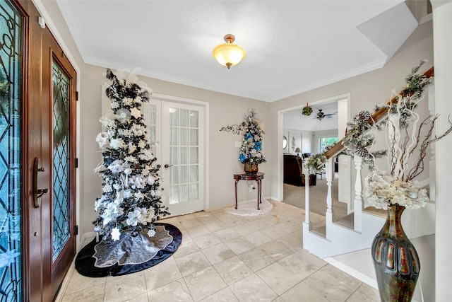 tiled foyer with french doors, a textured ceiling, and ornamental molding