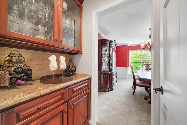 bar featuring an inviting chandelier, tasteful backsplash, light stone counters, crown molding, and light carpet