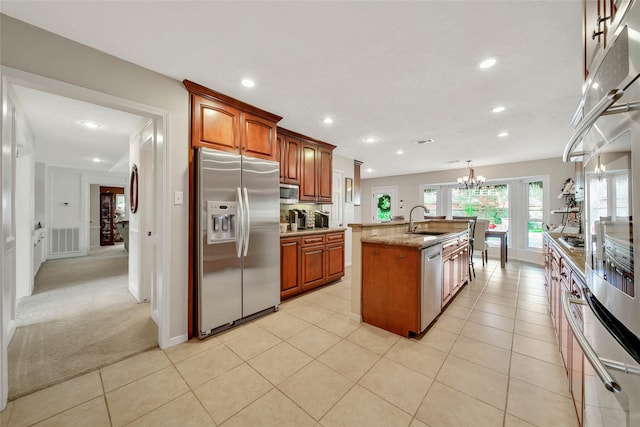 kitchen featuring an inviting chandelier, sink, an island with sink, light colored carpet, and stainless steel appliances