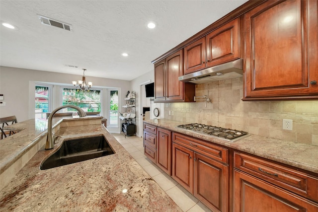 kitchen with sink, light stone countertops, tasteful backsplash, decorative light fixtures, and stainless steel gas cooktop