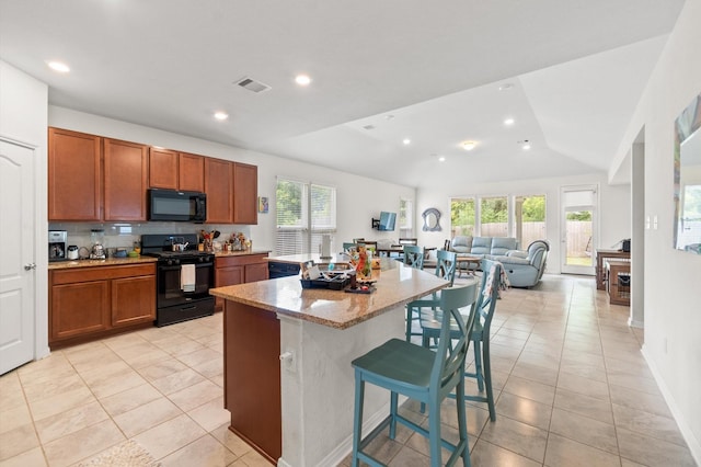 kitchen featuring a breakfast bar, lofted ceiling, black appliances, a kitchen island, and light stone counters