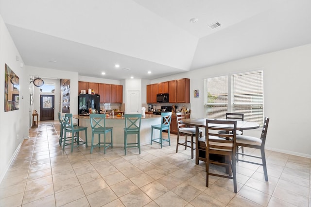 dining room with light tile patterned flooring and vaulted ceiling