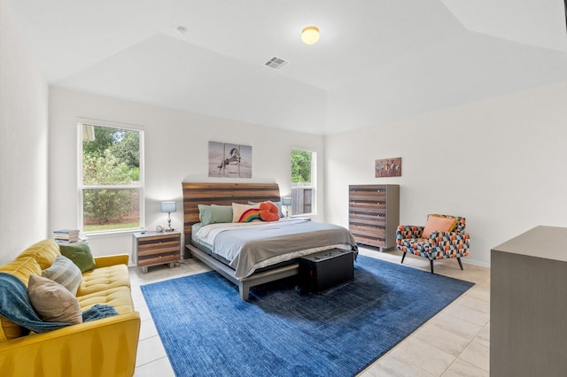 bedroom with light tile patterned floors and a tray ceiling