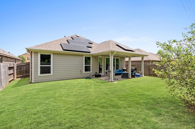 rear view of property featuring a lawn, a patio, an outdoor hangout area, and solar panels