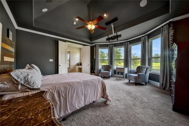 carpeted bedroom featuring a raised ceiling, ceiling fan, and ornamental molding