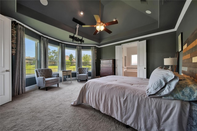 bedroom with carpet flooring, a tray ceiling, ensuite bath, and ceiling fan