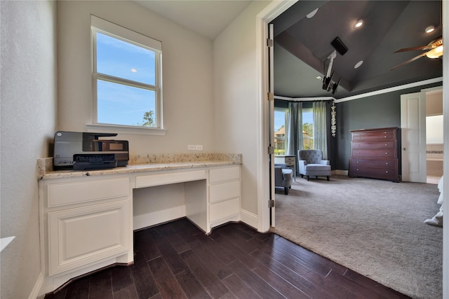 home office featuring ceiling fan, built in desk, vaulted ceiling, and dark colored carpet