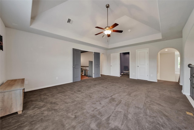 unfurnished bedroom featuring a tray ceiling, connected bathroom, and dark carpet