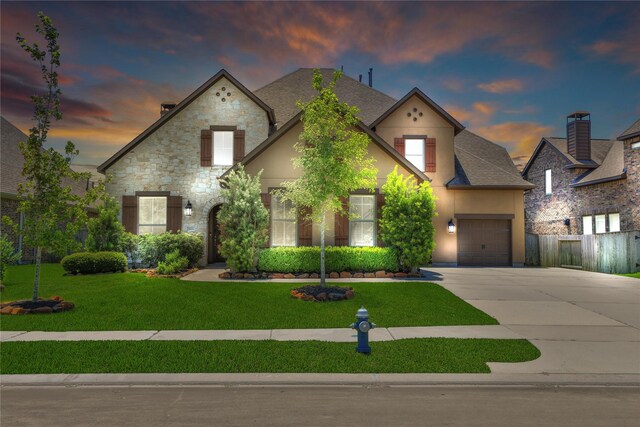 french provincial home with a yard and a garage