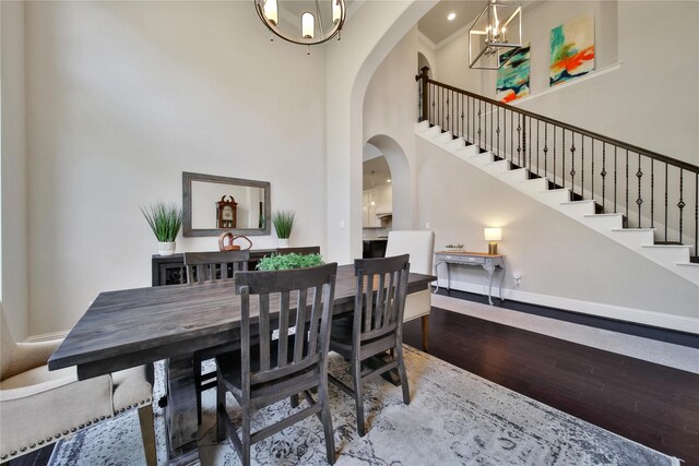 dining area featuring wood-type flooring, a high ceiling, and a notable chandelier