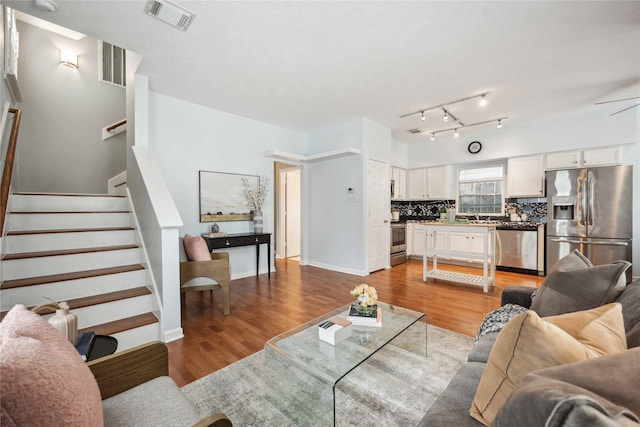 living room featuring ceiling fan, light hardwood / wood-style floors, and sink