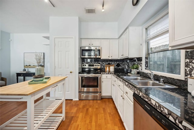 kitchen with track lighting, sink, light hardwood / wood-style floors, white cabinetry, and stainless steel appliances