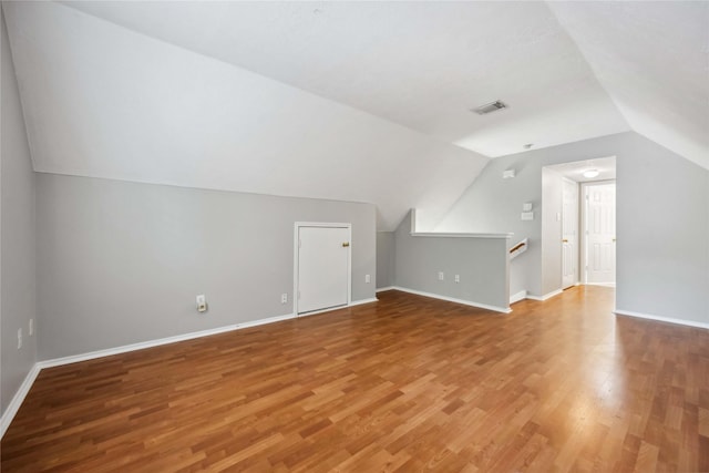 additional living space with wood-type flooring and vaulted ceiling