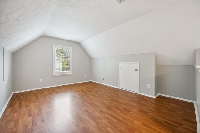 bonus room featuring a textured ceiling, wood-type flooring, and vaulted ceiling