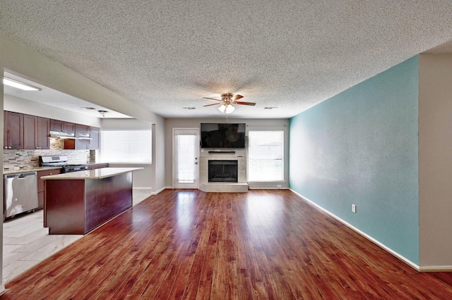 kitchen featuring stainless steel appliances, ceiling fan, light hardwood / wood-style floors, a kitchen island, and a tiled fireplace