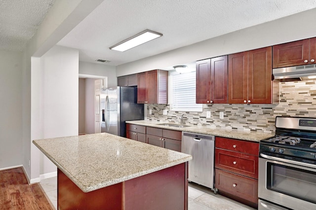 kitchen with backsplash, exhaust hood, sink, a kitchen island, and stainless steel appliances