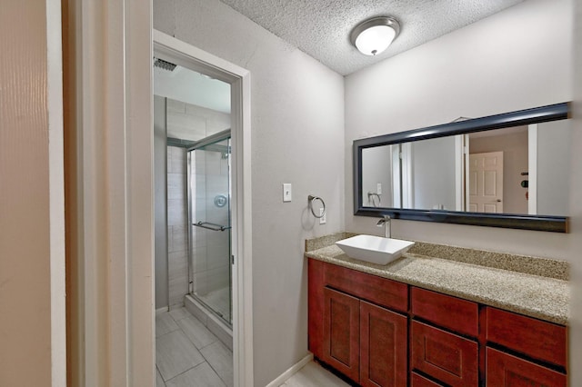 bathroom featuring vanity, a textured ceiling, a shower with shower door, and tile patterned flooring