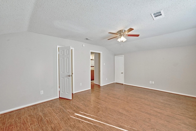 empty room featuring hardwood / wood-style floors, ceiling fan, a textured ceiling, and vaulted ceiling