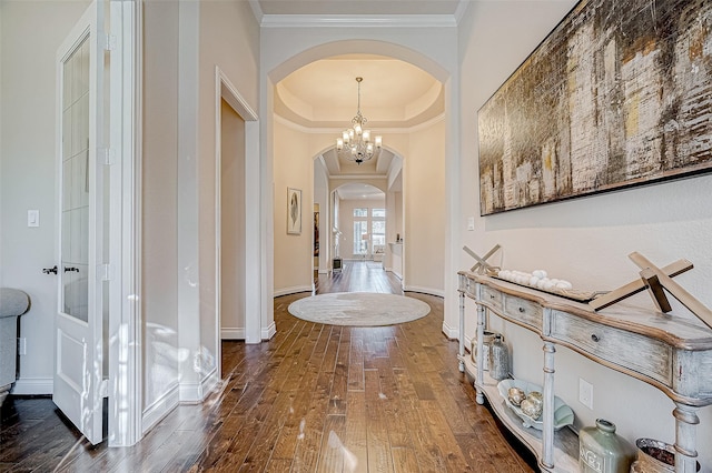 hallway with french doors, ornamental molding, a tray ceiling, an inviting chandelier, and dark hardwood / wood-style floors