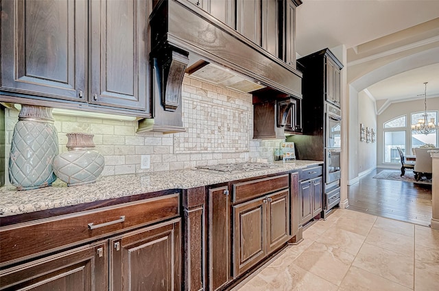 kitchen with pendant lighting, a notable chandelier, dark brown cabinets, and stainless steel appliances