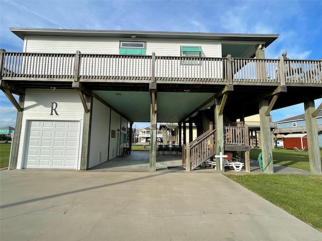 exterior space with concrete driveway, a garage, a deck, a carport, and a front lawn