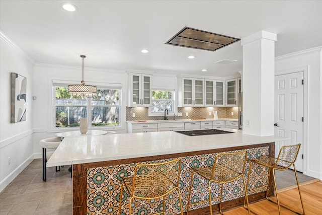 kitchen featuring black electric stovetop, crown molding, sink, pendant lighting, and white cabinets