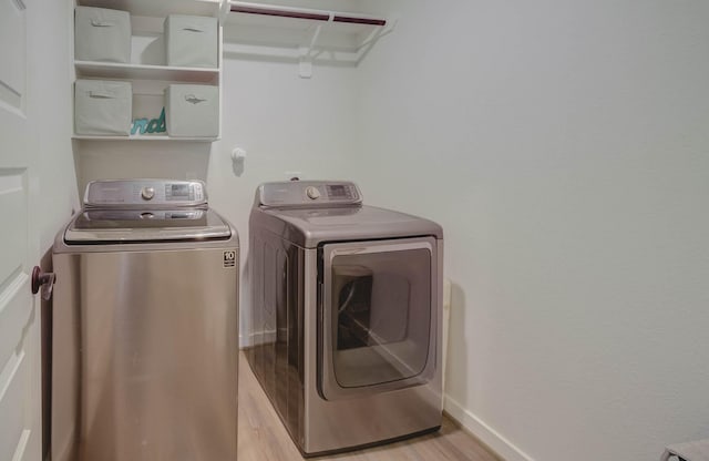 laundry room with washing machine and dryer and light hardwood / wood-style flooring