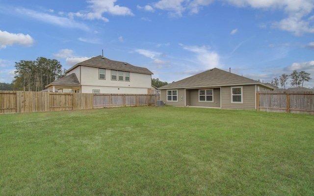 rear view of house with central air condition unit and a yard