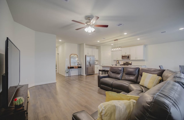 living room with ceiling fan and light hardwood / wood-style flooring