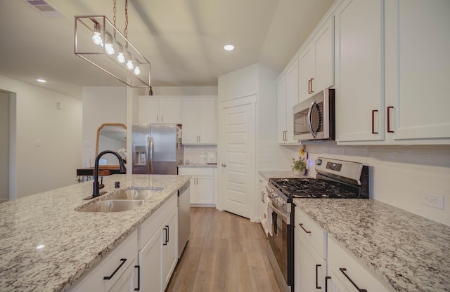 kitchen featuring light stone countertops, white cabinetry, sink, stainless steel appliances, and light hardwood / wood-style flooring