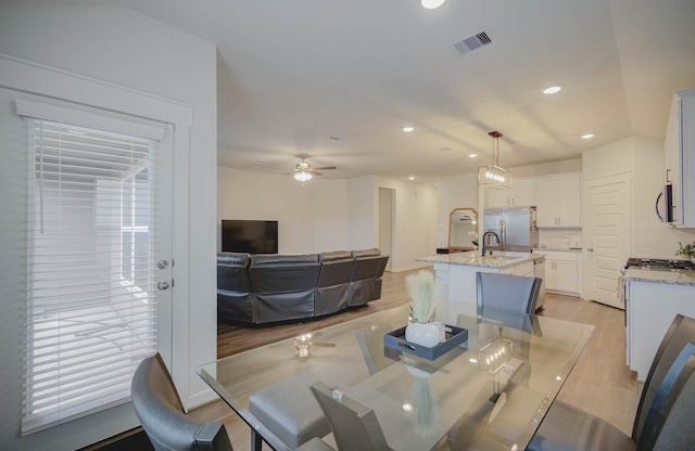 dining space with ceiling fan, light hardwood / wood-style floors, and sink