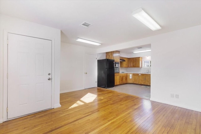 unfurnished living room featuring sink and light wood-type flooring