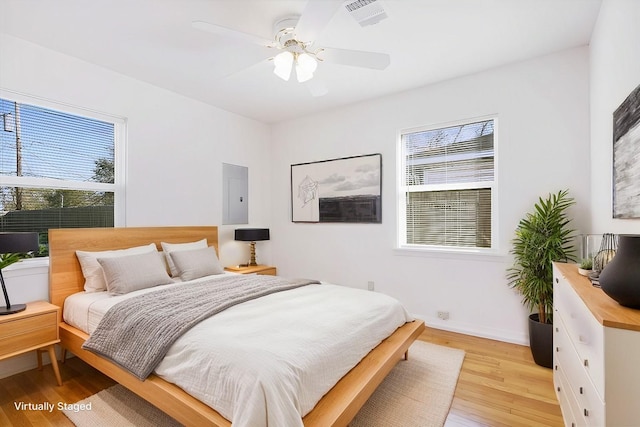 bedroom with electric panel, ceiling fan, and light hardwood / wood-style floors