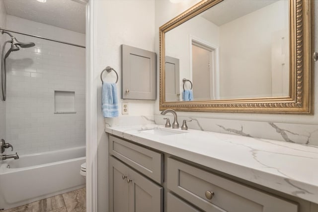 full bathroom featuring vanity, toilet, a textured ceiling, and tiled shower / bath combo