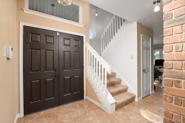 tiled foyer entrance with a notable chandelier