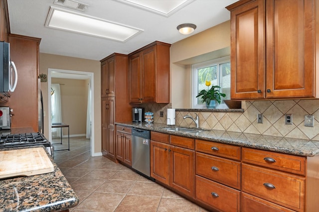 kitchen with dishwasher, dark stone counters, sink, decorative backsplash, and light tile patterned flooring