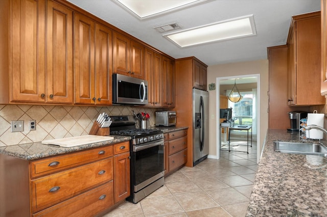 kitchen with backsplash, sink, light tile patterned flooring, and stainless steel appliances