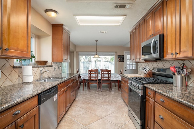 kitchen featuring decorative backsplash, stainless steel appliances, dark stone counters, and sink