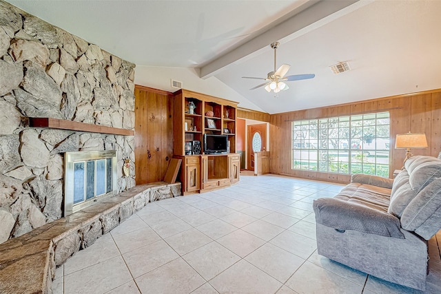 tiled living room featuring a fireplace, vaulted ceiling with beams, ceiling fan, and wood walls