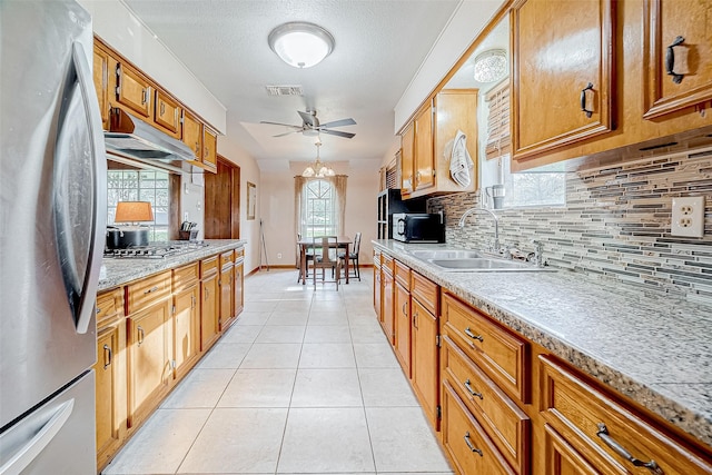 kitchen featuring tasteful backsplash, ceiling fan with notable chandelier, stainless steel appliances, sink, and light tile patterned floors