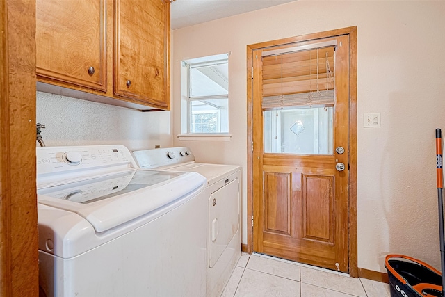 clothes washing area with cabinets, light tile patterned floors, and washer and clothes dryer