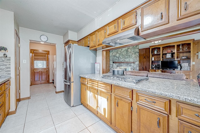 kitchen with a fireplace, light tile patterned flooring, light stone countertops, and stainless steel appliances